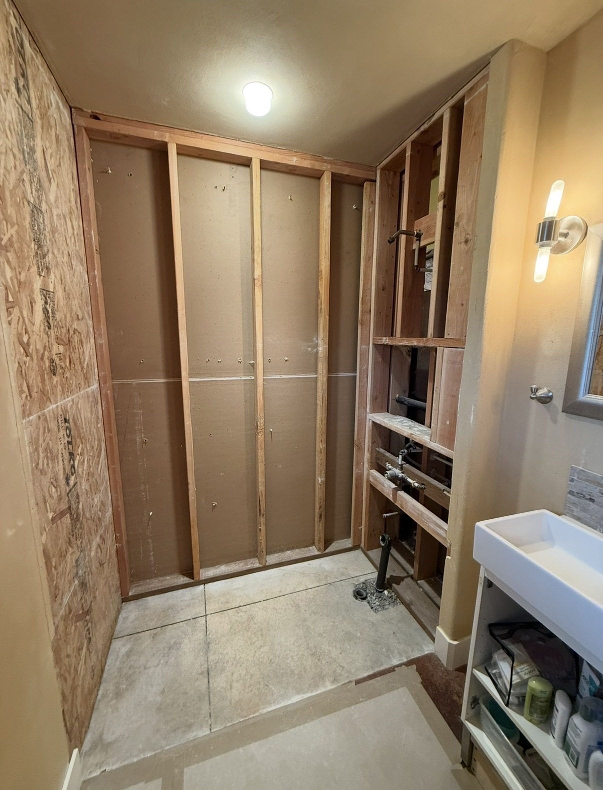 The same wall stripped to the studs, old plumbing exposed
