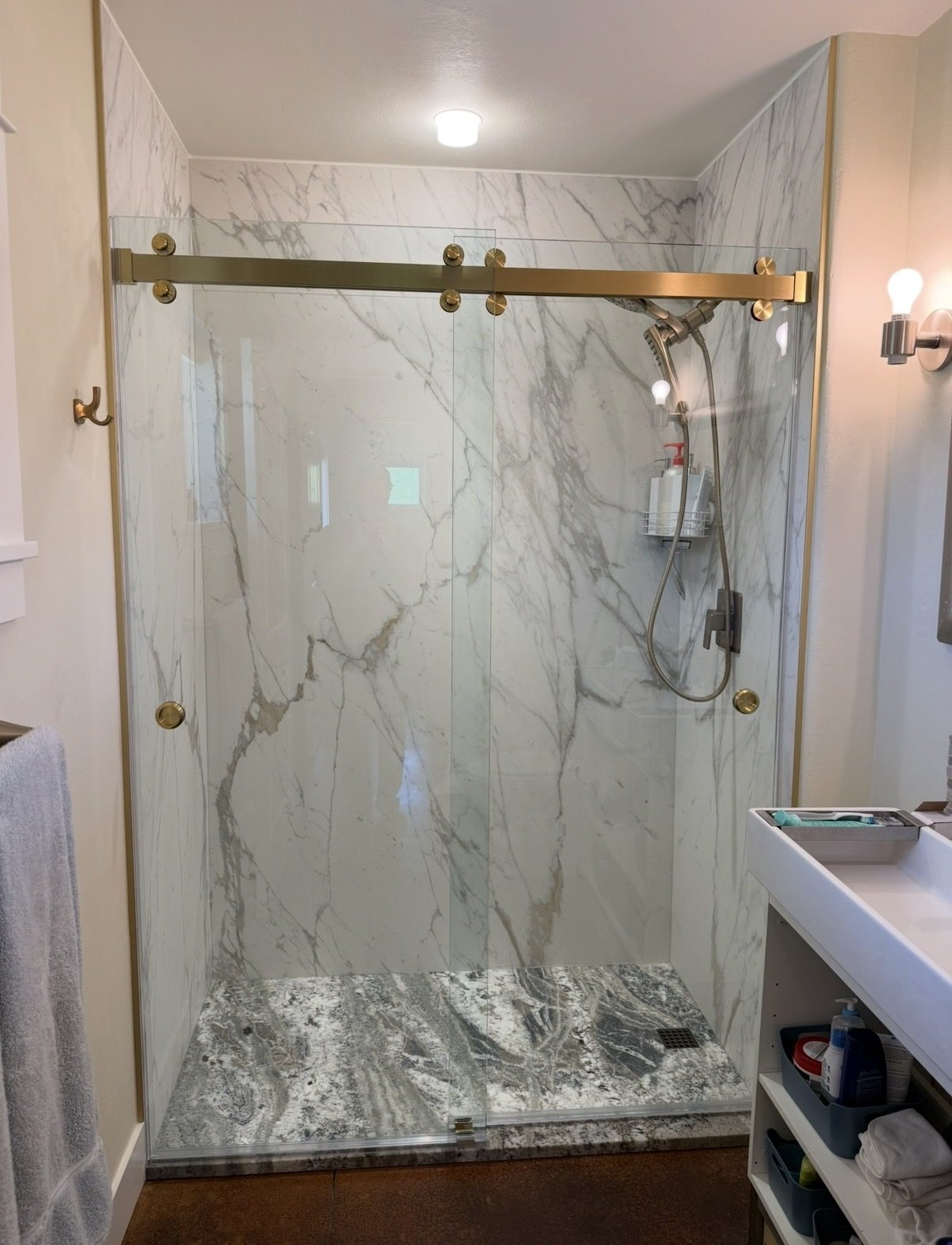 Finished walk-in shower with stone walls and frameless glass