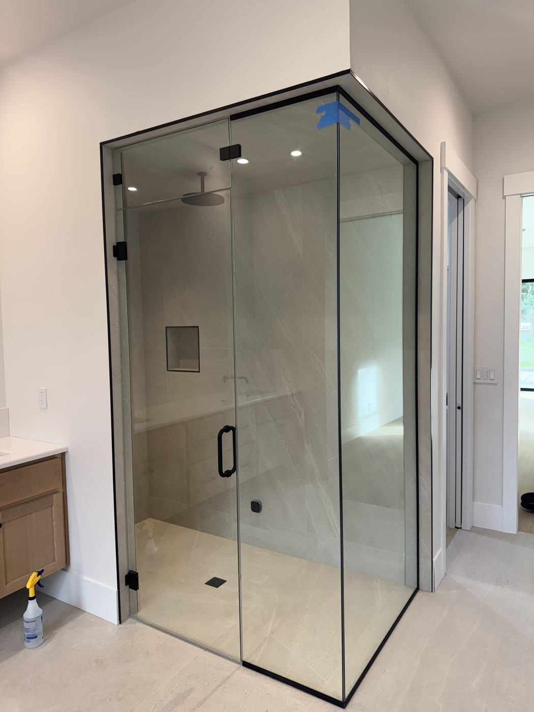 Corner shower enclosure with black-framed glass and stone-look tile